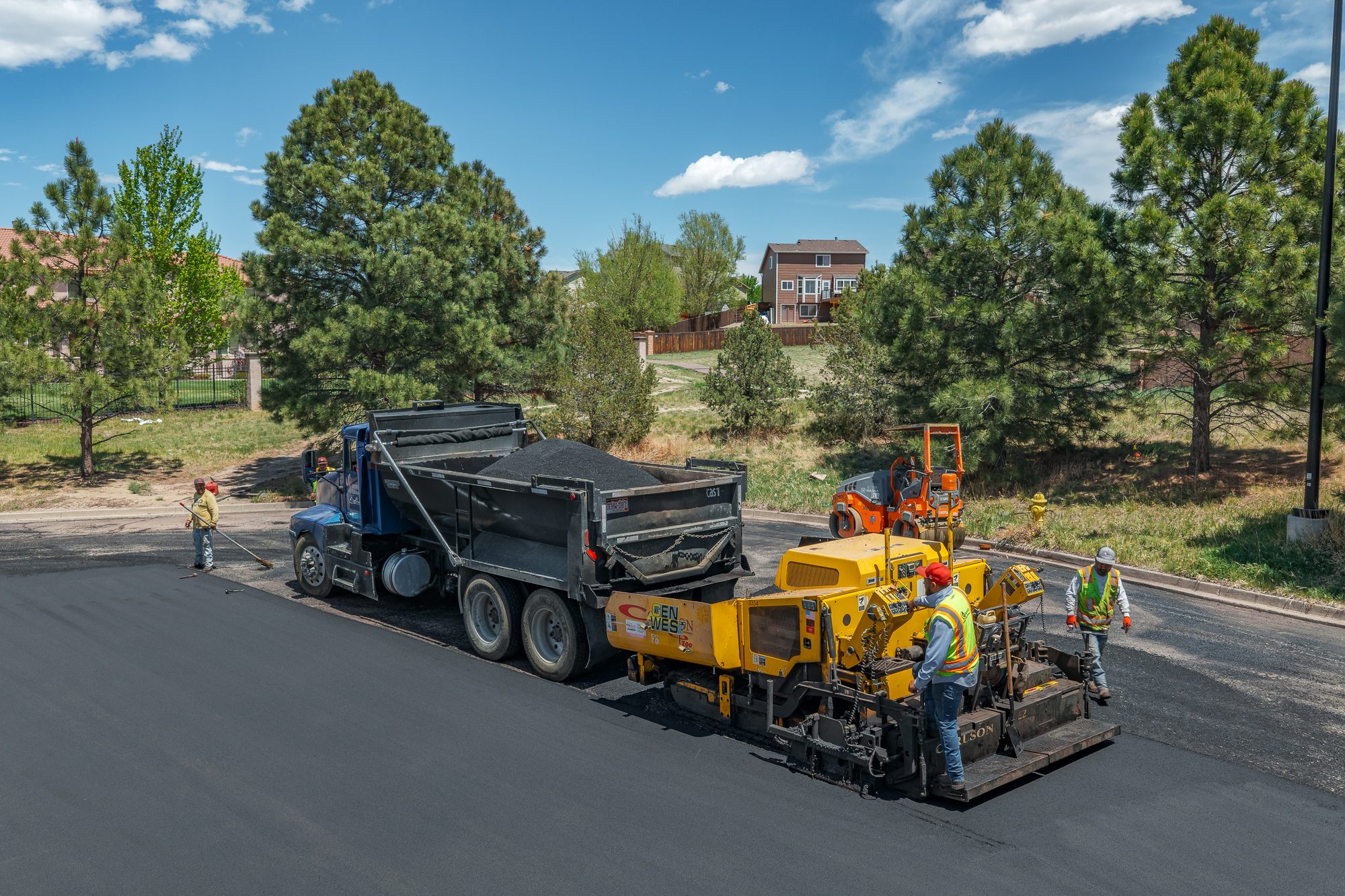 Gen West crew paving a commercial parking lot with a paver and dump truck