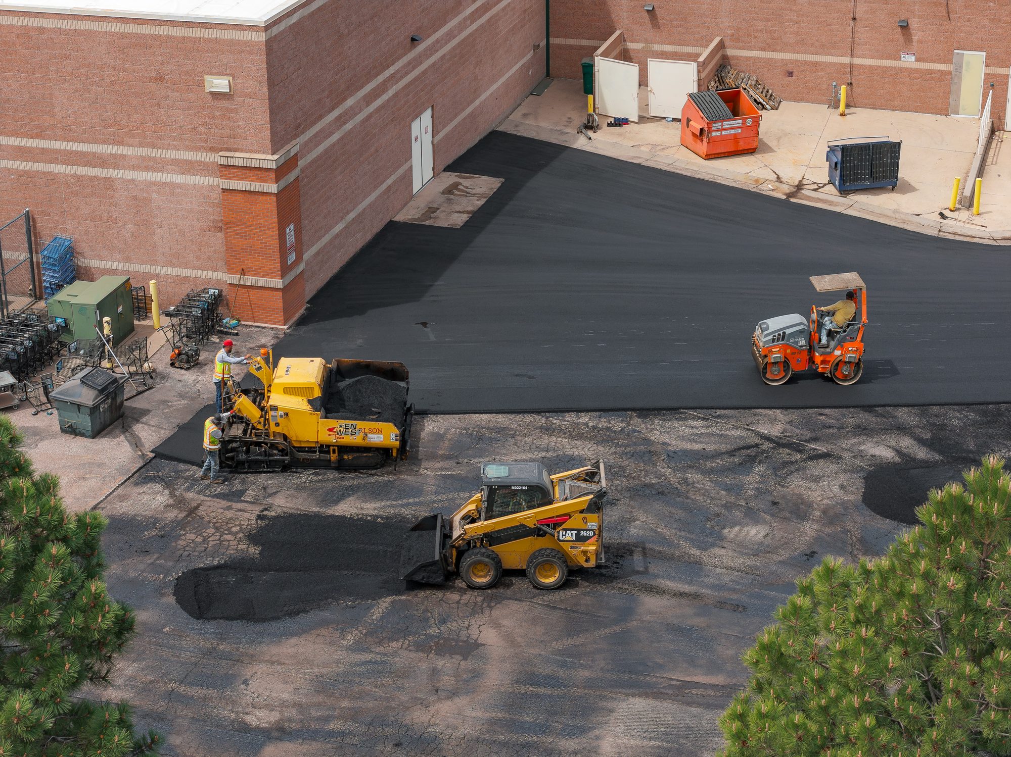 Gen West crew at work on a commercial paving project with paver, roller, and skid steer