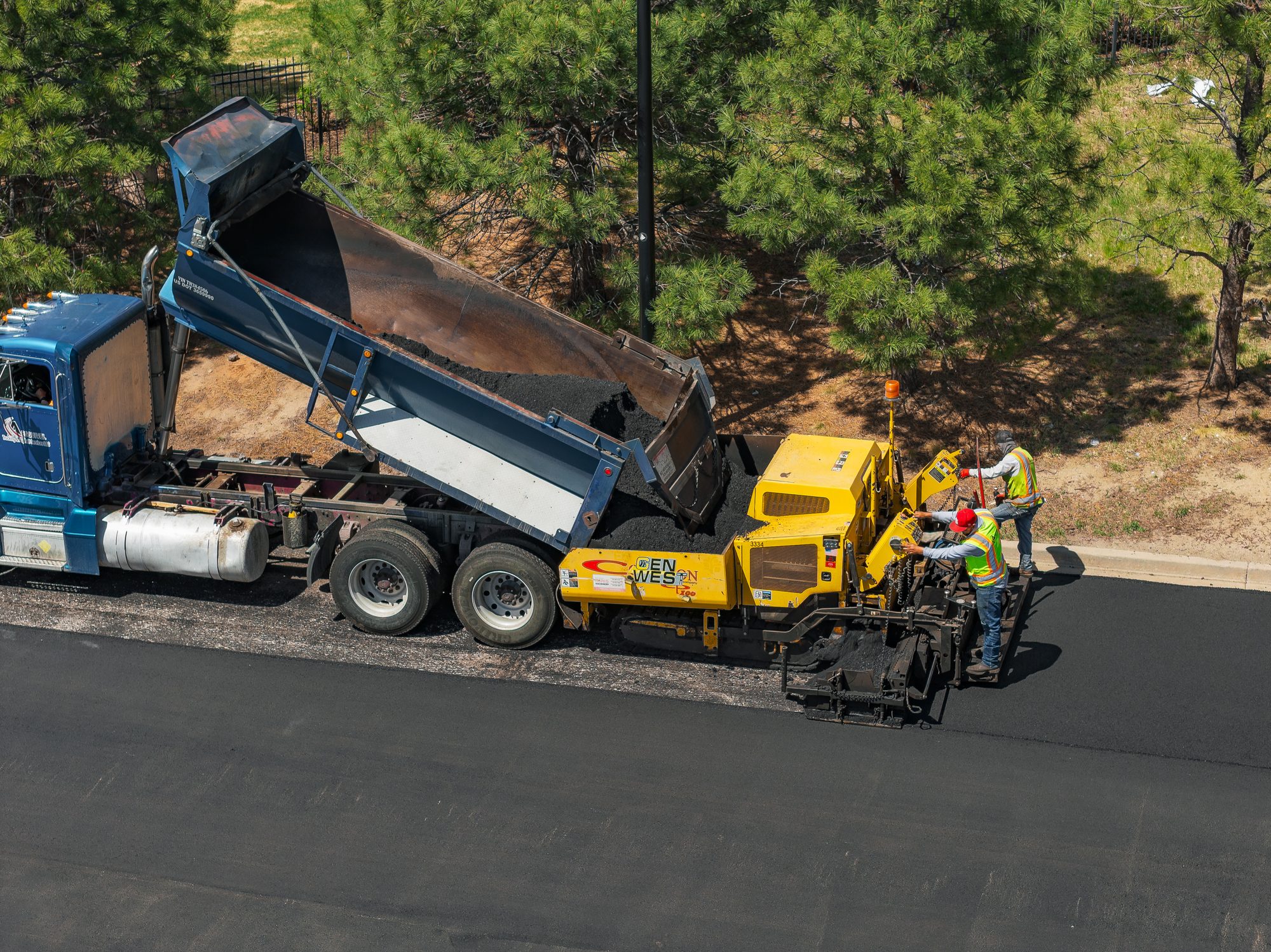 Asphalt paving with a Gen West paver receiving material from a dump truck
